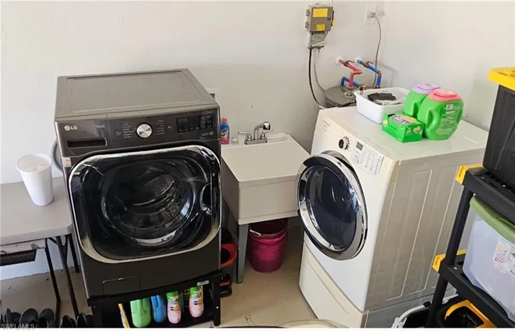 Laundry room with a sink, laundry area, and independent washer and dryer
