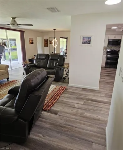 Living area with baseboards, ceiling fan, wood finished floors, and visible vents