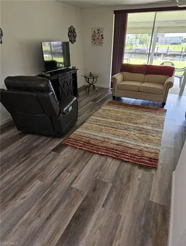 Living room featuring dark wood-type flooring and baseboards