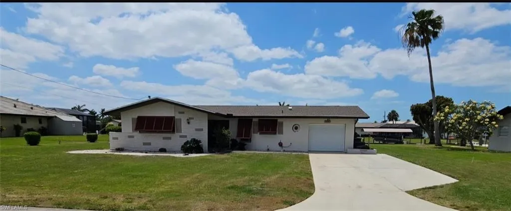 Single story home featuring an attached garage, concrete driveway, and a front lawn