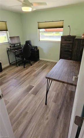 Office space with a ceiling fan, baseboards, a healthy amount of sunlight, and wood finished floors
