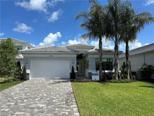 View of front of house featuring a garage, stucco siding, decorative driveway, and a front yard