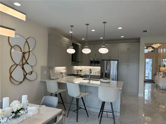 Kitchen with a peninsula, marble finish floor, stainless steel appliances, and a sink