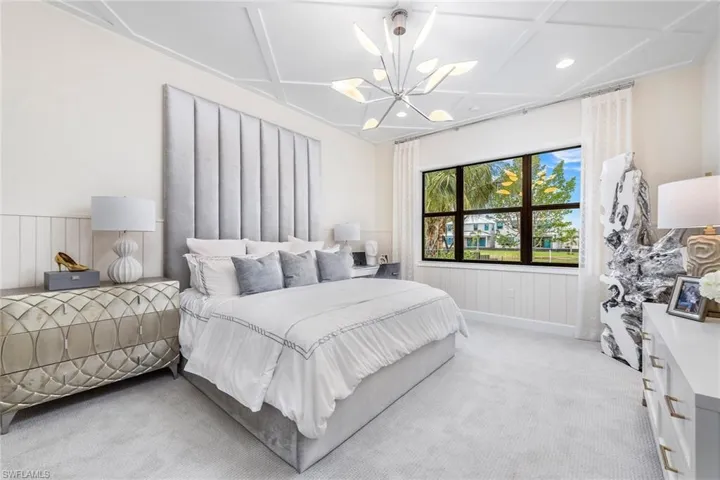 Bedroom featuring light carpet, beamed ceiling, coffered ceiling, and a chandelier