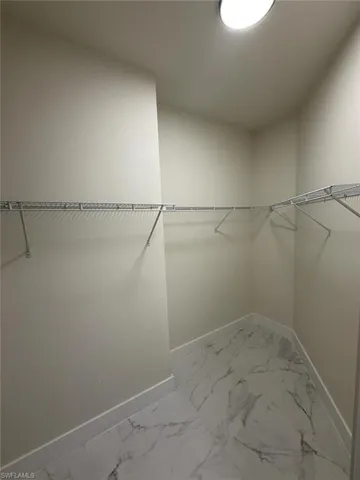 Walk in closet featuring marble finish flooring