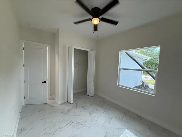 Unfurnished bedroom featuring marble look tiles, a closet, and a ceiling fan