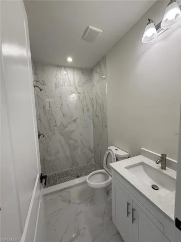 Full bath with a marble finish shower, vanity, and marble finish flooring