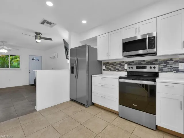 Kitchen with stainless steel appliances, light countertops, white cabinetry, a ceiling fan, and recessed lighting