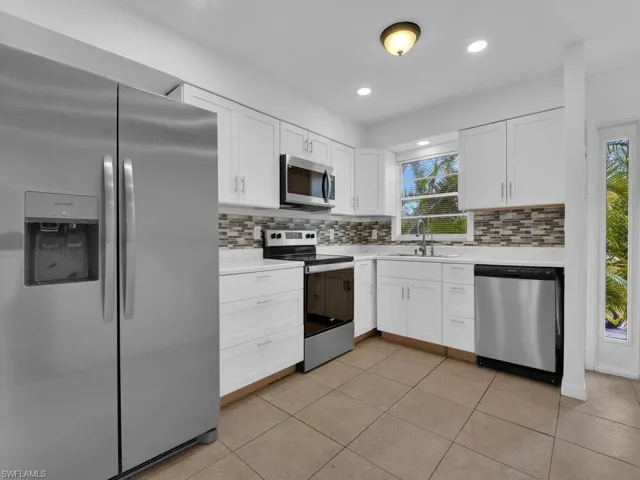 Kitchen featuring stainless steel appliances, white cabinets, light tile patterned floors, recessed lighting, and tasteful backsplash