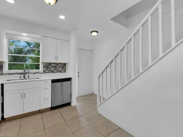 Kitchen with white cabinetry, dishwasher, backsplash, light tile patterned floors, and recessed lighting