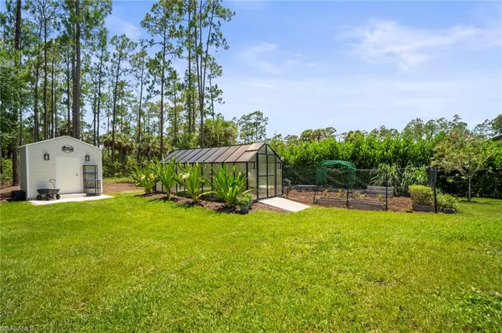 View of grassy yard with an exterior structure, a vegetable garden, and an outbuilding