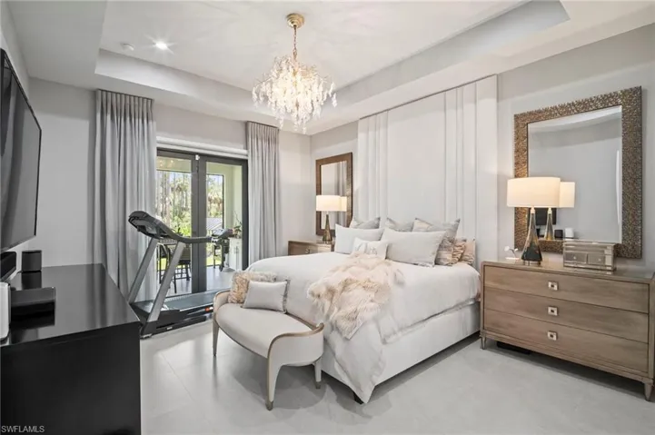 Bedroom with a chandelier, access to outside, and a tray ceiling