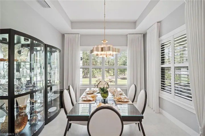 Dining room featuring a tray ceiling, light tile patterned floors, and a chandelier