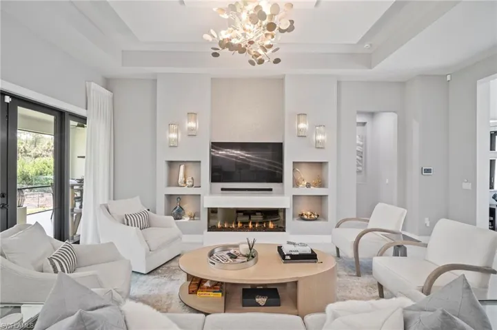Living room featuring built in features, a chandelier, and a tray ceiling