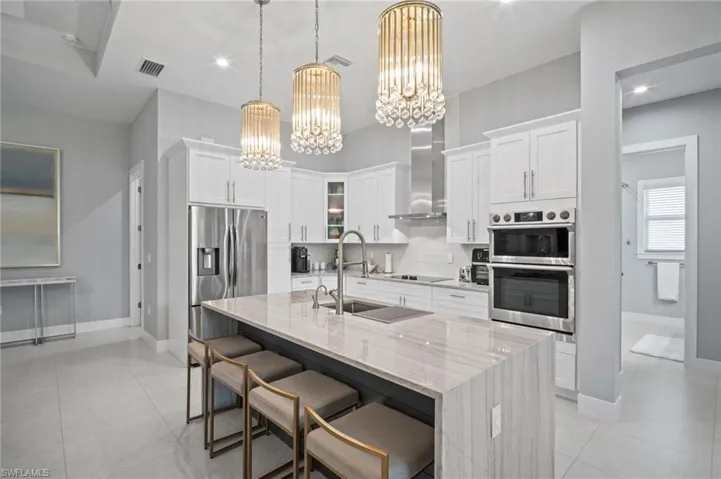 Kitchen featuring a chandelier, decorative backsplash, stainless steel appliances, white cabinetry, and recessed lighting