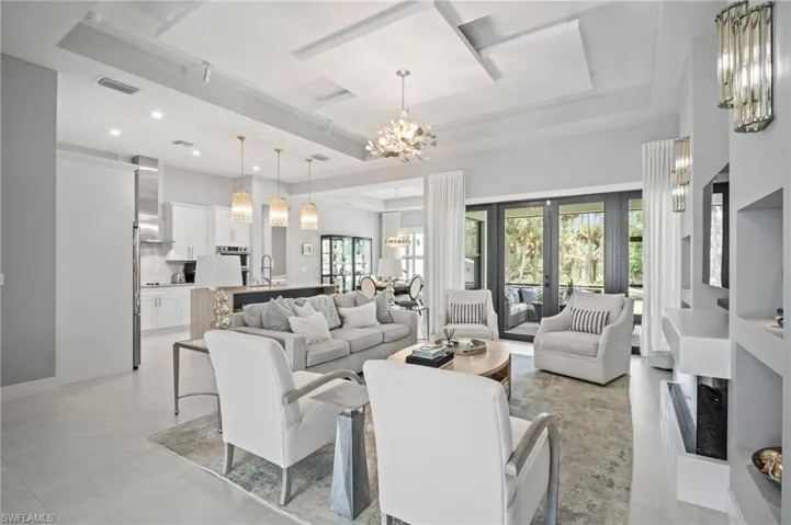 Living room with a chandelier, french doors, recessed lighting, light tile patterned floors, and a raised ceiling