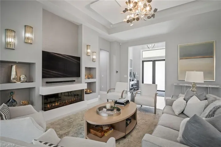 Living area featuring built in features, a chandelier, and a glass covered fireplace