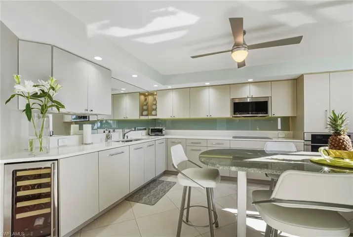 Kitchen featuring beverage cooler, recessed lighting, stainless steel appliances, ceiling fan, and a kitchen bar