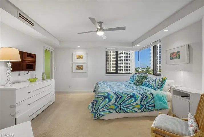 Bedroom featuring light carpet, recessed lighting, ceiling fan, and a tray ceiling