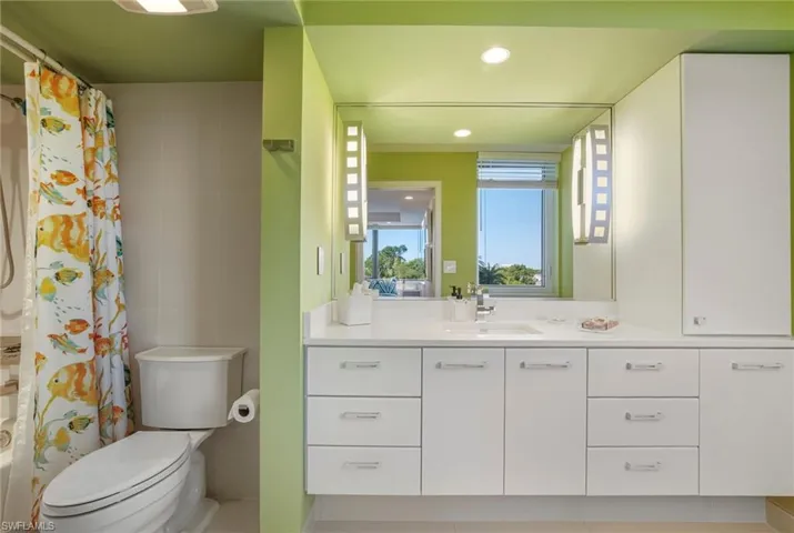 Full bathroom featuring vanity, shower / bath combo, recessed lighting, and tile walls