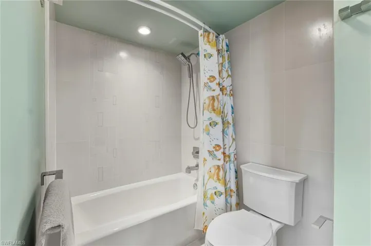 Full bathroom with shower / bath combo with shower curtain, tile walls, and recessed lighting