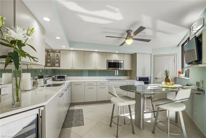 Kitchen featuring wine cooler, a kitchen breakfast bar, light stone countertops, stainless steel appliances, and recessed lighting