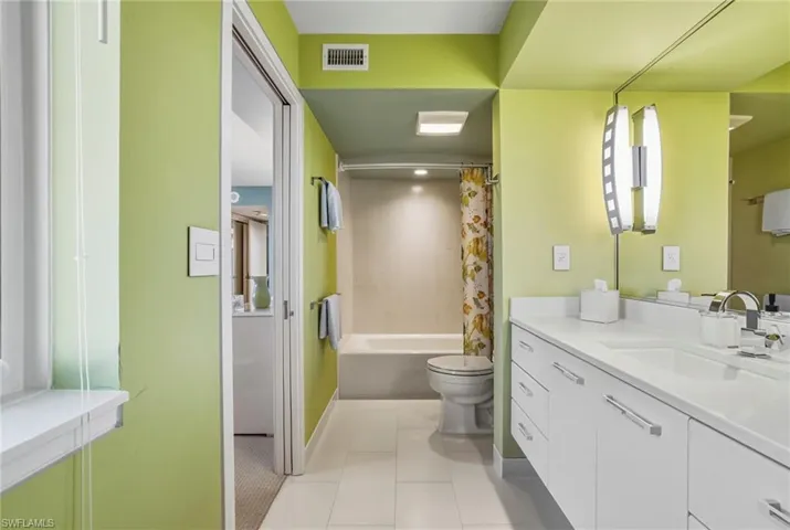 Bathroom with vanity, shower / bathtub combination with curtain, and light tile patterned floors