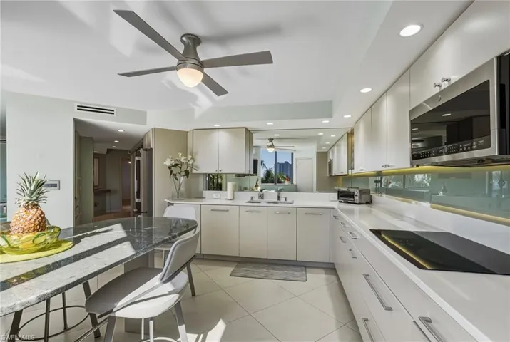 Kitchen with stainless steel appliances, recessed lighting, light tile patterned flooring, a breakfast bar, and white cabinetry