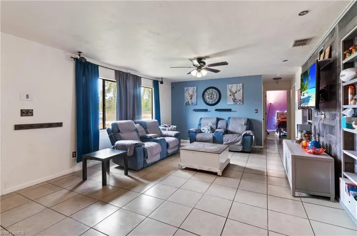 Living area with ceiling fan and light tile patterned floors