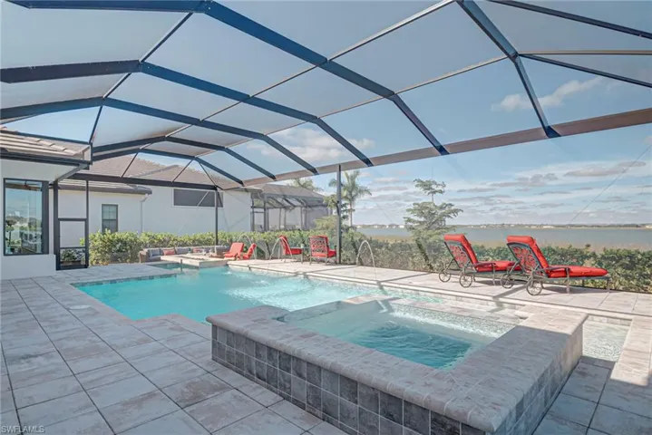 View of swimming pool with a patio area, a lanai, a sunroom, a pool with connected hot tub, and a water view