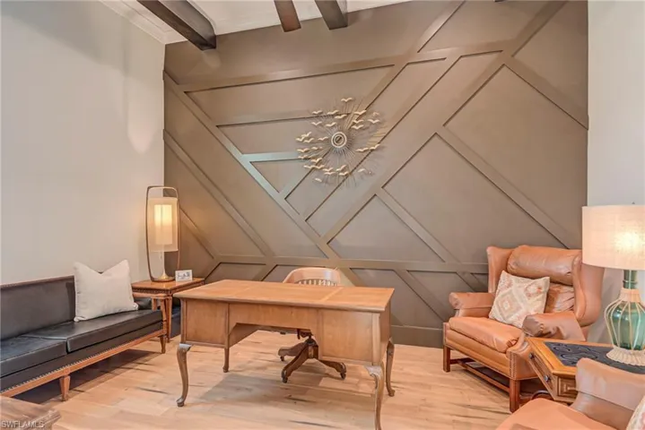 Home office featuring a decorative wall, beam ceiling, and crown molding