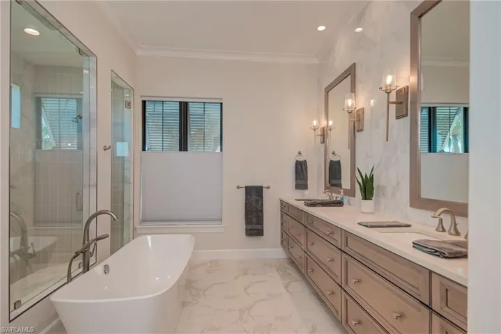 Bathroom with a soaking tub, recessed lighting, double vanity, a shower stall, and crown molding