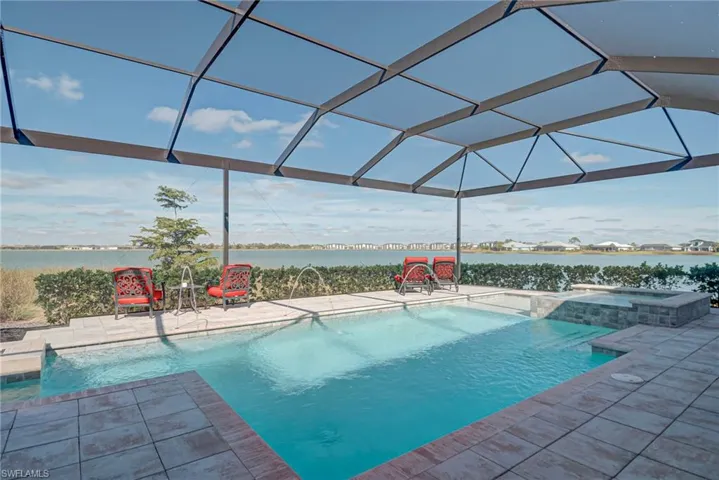 Swimming pool featuring an in-ground hot tub, a lanai, a water view, and a patio area