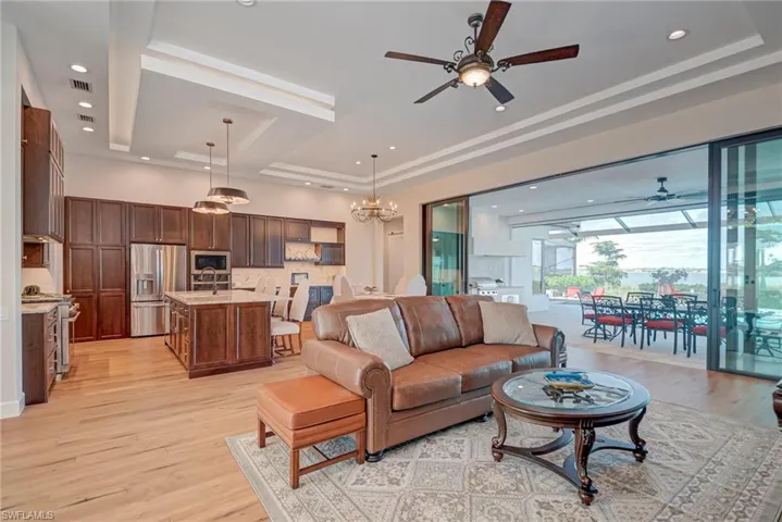 Living area featuring a tray ceiling, light wood-style flooring, ceiling fan, and recessed lighting