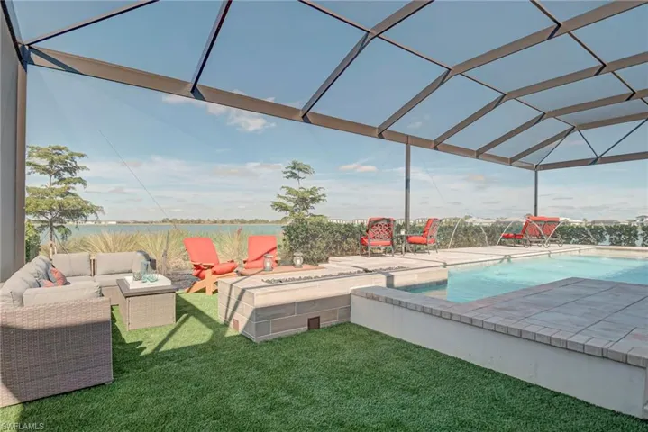 Swimming pool featuring a sunroom, a water view, a yard, a patio, and glass enclosure