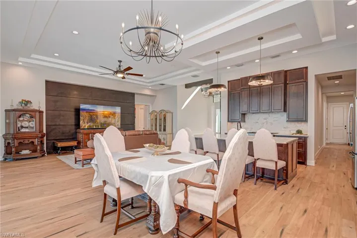 Dining room featuring recessed lighting, light wood finished floors, a ceiling fan, a raised ceiling, and a chandelier