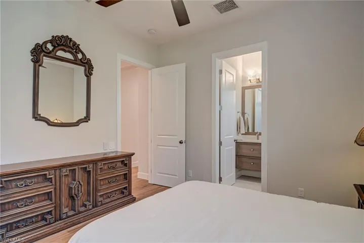 Bedroom with a ceiling fan, light wood-type flooring, and ensuite bathroom