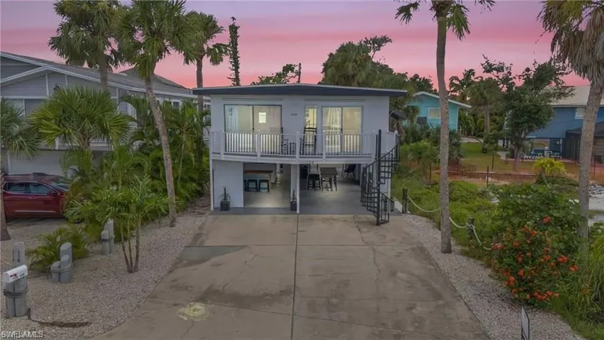 View of front of house featuring stucco siding, a porch, a carport, driveway, and stairs