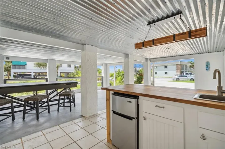 Kitchen featuring stainless steel refrigerator, white cabinets, butcher block counters, sink, and light tile patterned flooring