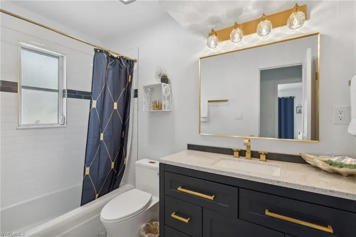 Full bathroom featuring toilet, shower / tub combo, and vanity