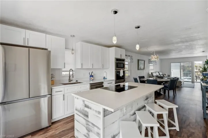 Kitchen with stainless steel appliances, dark hardwood / wood-style flooring, white cabinetry, and sink