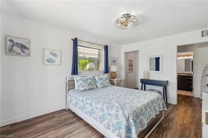 Bedroom with ensuite bath and dark hardwood / wood-style flooring