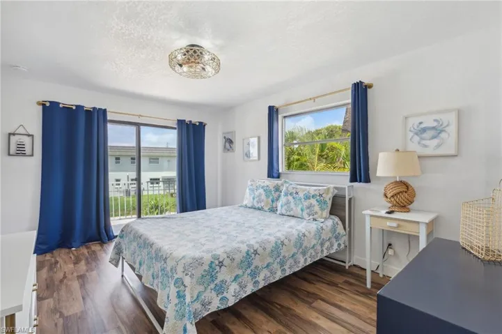 Bedroom with a textured ceiling, dark hardwood / wood-style floors, and multiple windows