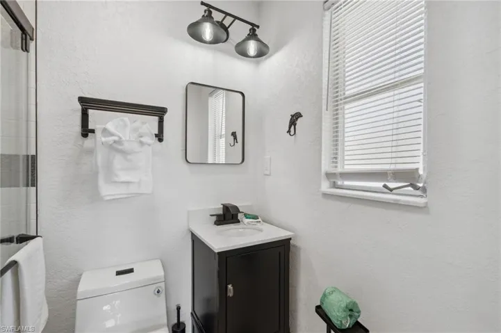 Bathroom with a shower with shower door, toilet, and vanity