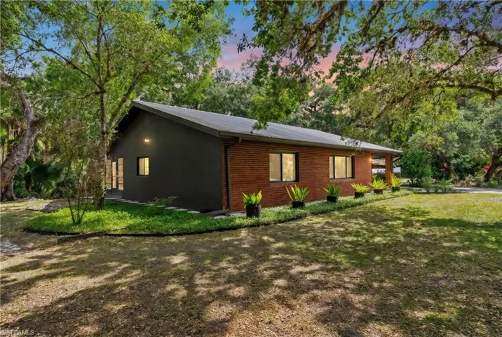 Side view on home shaded with mature live oaks.