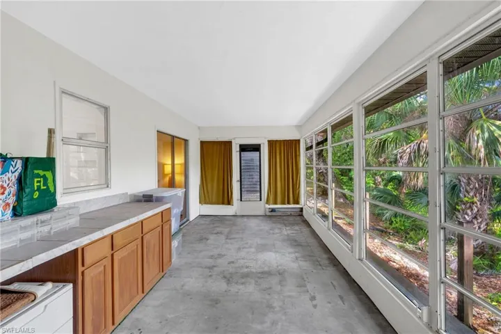 An additional Florida room overlooking the wooded backdrop offers excellent potential for expanded living space, a private retreat, office, or future suite enhancement.