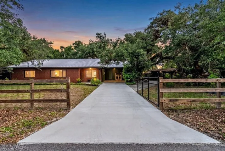 Front entrance view, concrete driveway with gated entrance.