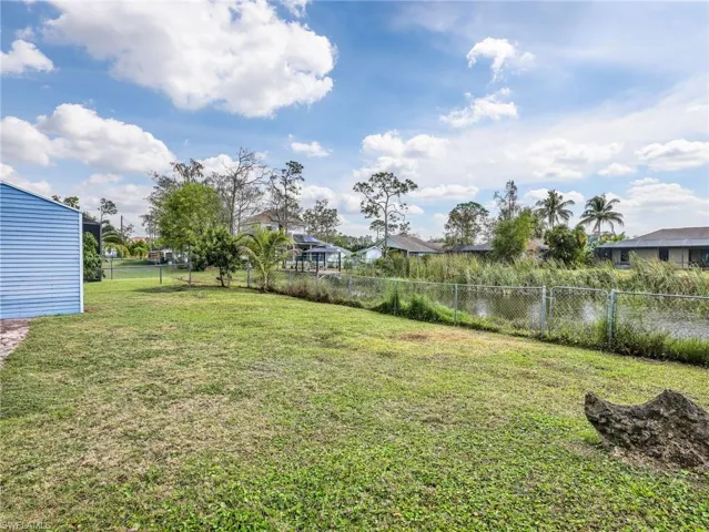 Expansive green lawn with a chain-link fence bordering a canal