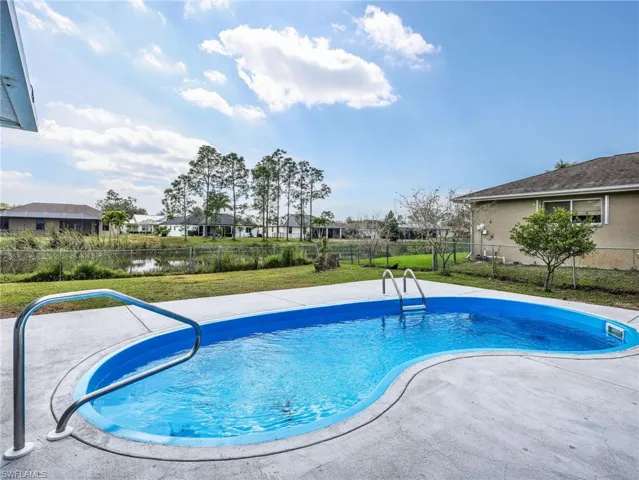 Freeform swimming pool with concrete decking, stainless steel handrails, and an integrated ladder