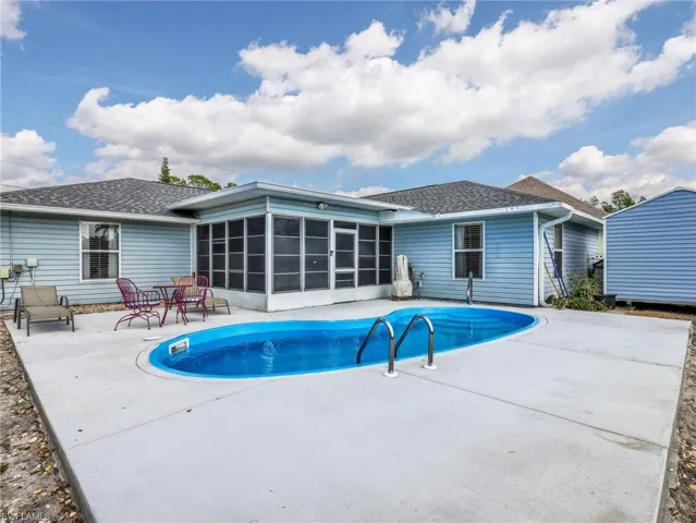 Rear exterior featuring a screened-in patio, an in-ground swimming pool, and a dedicated concrete deck